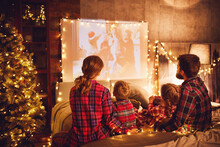 Family Mother Father And Children Watching Projector, Film, Movies With Popcorn In   Christmas Evening   At Home.