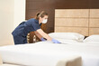 Chambermaid in uniform is busy while cleaning the bedroom