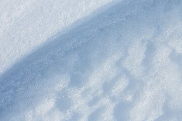 Beautiful winter background with snowy ground. Natural snow texture. Wind sculpted patterns on snow surface. Closeup top view with copy space.