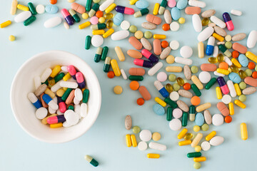 Wall Mural - Colorful pills, capsules and supplements on white plate on light blue background. Minimal modern pharmacy or health care concept. Flat lay, top view