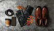 Flat lay composition with stylish black leather gloves, male shoes and dry leaves on grey table