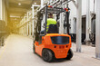 © Алина Бузунова - Storehouse employee in uniform working on forklift in modern automatic warehouse. Boxes are on the shelves of the warehouse. Warehousing, machinery concept. Logistics in stock.