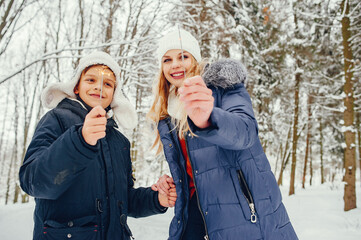 Beautiful mother in a blue jacket. Family playing in a winter park. Little boy in a cute hat