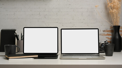 Worktable with two laptops, stationery, supplies and decorations in home office room