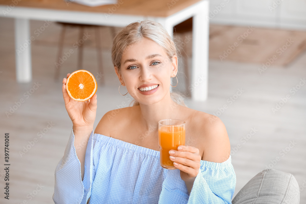 Beautiful young woman drinking orange juice at home