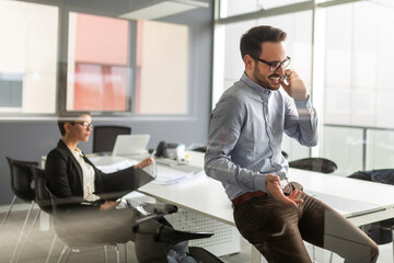 Handsome successful businessman on a phone in the office.