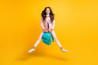 Full size photo of brunette wavy haired funky happy girl jump up hold school bag isolated on yellow color background