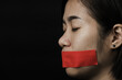 © sorapop - Asian woman blindfold wrapping mouth with red adhesive tape on black background. Freedom speech censorship and stop talk, International Human Right day