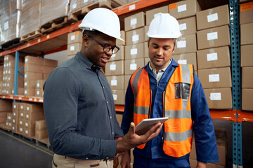 Multi ethnic factory engineers checking digital tablet at factory warehouse