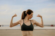 © face_reader_img - Headshot of young sporty woman showing biceps posing outdoor.