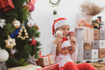 Wall Mural - cheerful cute childrens girls with gifts. kids wearing pajamas having fun near tree in the morning. merry christmas and happy holidays.  loving family with presents in room.