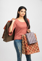 Wall Mural - Pretty Indian young woman with shopping bags and on white.