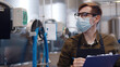 © TommyStockProject - Worker in safety mask controlling data on production line in beer factory.