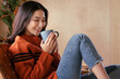 © JR-50 - Portrait of a young Asian woman wearing a sweater. She inhaled the scent and drank the winter morning coffee. She smiles and enjoys being relaxed at home.