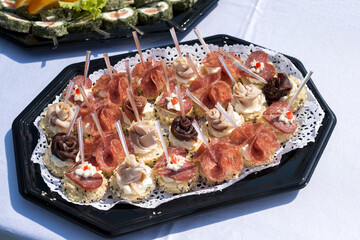 The buffet at the reception. Assortment of canapes on a table. Banquet service. Catering food, snacks with different types of cheese, ham, salami, prosciutto, shrimp, vegetables and fruits. Party Conc