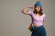 Happy woman showing her bicep while posing with rainbow flag