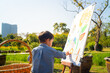 Asian kid boy drawing paint on paper in flower outdoor park