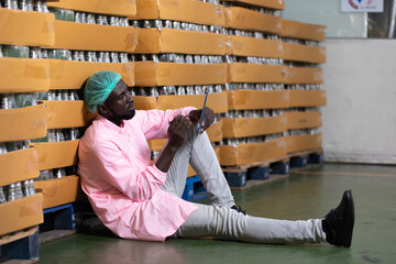 Wall Mural - African male factory worker holding pen and writing on clipboard in beverage factory