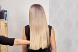 Fototapeta Tęcza - The view from the back on the long beautiful blonde hair. Shiny healthy hair. Professional hair care products.