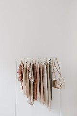 Wall Mural - Women's fashion bright pastel clothes on hanger on white background. Minimalist fashion blog concept.