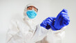 © M-Production - Medical worker in protective suit puts on gloves.