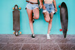 © VISTA by Westend61 - Lesbian couple holding cigarettes standing by skateboards on footpath against wall
