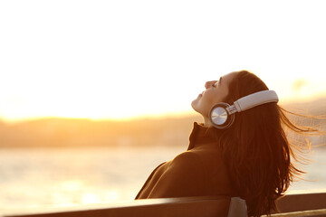 Woman listening to music breathing on a bench in winter