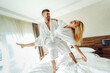 © dusanpetkovic1 - A cheerful middle-aged couple in bathrobes celebrating their anniversary in a hotel. A man holding a woman in his hands.