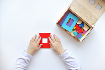 Learning colors and shapes. Children's wooden toy. The child collects a sorter. Educational logic toys for kid's. Children's hands close-up. Montessori Games for Child Development