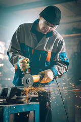 Wall Mural - Locksmith in special clothes and goggles works in production. Metal processing with angle grinder. Sparks in metalworking