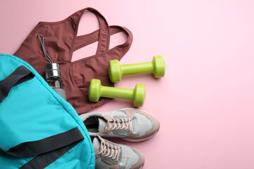 Wall Mural - Flat lay composition with sportswear, gym bag and dumbbells on pink background, space for text