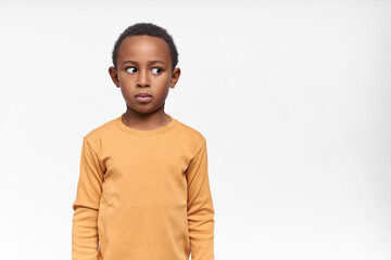 Poster - Cute funny dark skinned little boy looking away with shameful or shy facial expression, trying to hide what he has done. Black child expressing fear, being afraid of scary sudden sound, holding breath