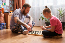 Father Teaching His Daughter How To Play Checkers
