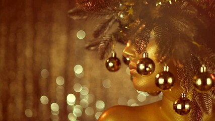 Wall Mural - Beauty Golden Christmas Woman wearing gold spruce wreath decorated with baubles. Golden skin Make-up for Party, glowing holiday background. Xmas, New Year Holiday celebration. Slow motion