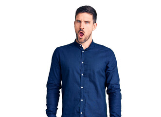 Sticker - Young handsome man wearing casual shirt in shock face, looking skeptical and sarcastic, surprised with open mouth