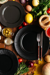 Wall Mural - black plates on a wooden background with vegetables and fruits l