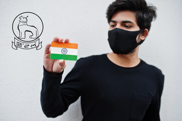 Indian man wear all black and face mask, hold India flag in hand isolated on white background with Manipur state emblem . Coronavirus India states and union territories concept.