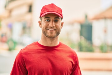 Sticker - Young caucasian deliveryman smiling happy standing at the city.