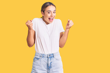 Young beautiful blonde woman wearing casual white tshirt celebrating surprised and amazed for success with arms raised and open eyes. winner concept.