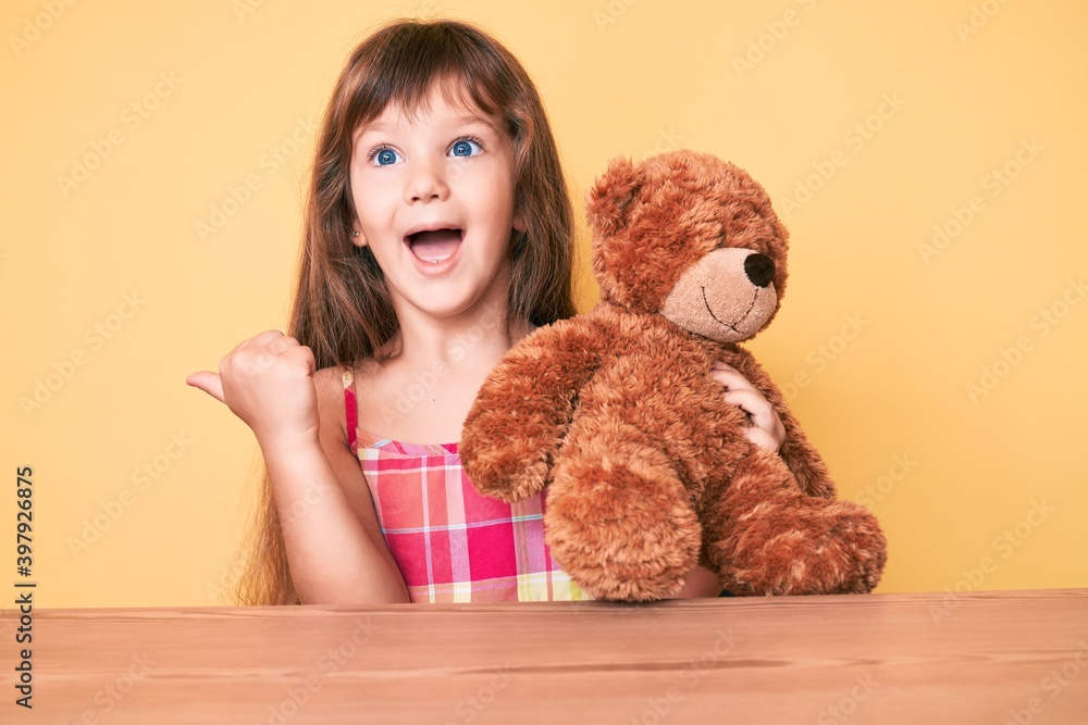Little caucasian kid girl with long hair sitting on the table with ...