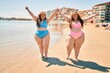 © Krakenimages.com - Two plus size overweight sisters twins women happy and proud of their bodies walking at the beach on summer holidays