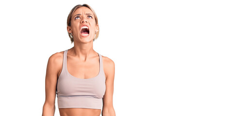 Beautiful caucasian woman wearing sportswear angry and mad screaming frustrated and furious, shouting with anger. rage and aggressive concept.