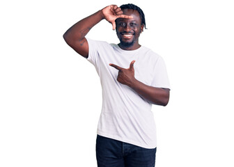 Sticker - Young african american man with braids wearing casual white tshirt smiling making frame with hands and fingers with happy face. creativity and photography concept.