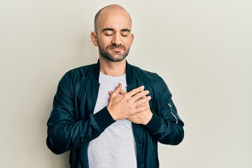 Canvas Print - Young hispanic man wearing casual sporty jacket smiling with hands on chest, eyes closed with grateful gesture on face. health concept.