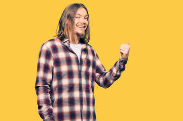 Sticker - Handsome caucasian man with long hair wearing hipster shirt smiling with happy face looking and pointing to the side with thumb up.