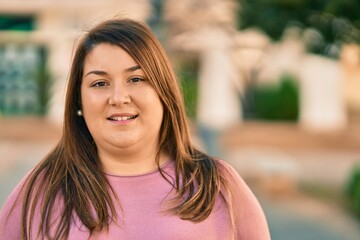 Young hispanic plus size woman smiling happy standing at the city.