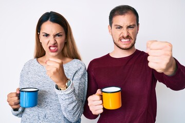 Beautiful couple holding coffee annoyed and frustrated shouting with anger, yelling crazy with anger and hand raised