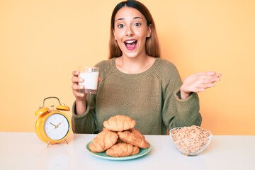 Sticker - Young brunette woman drinking a glass of milk for breakfast celebrating achievement with happy smile and winner expression with raised hand