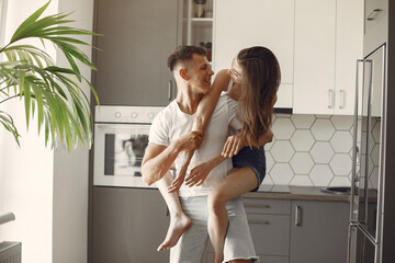 Cute couple in a kitchen. Lady in a white t-shirt. Pair at home