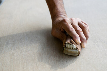 Old man hand working polishing wooden sheet board